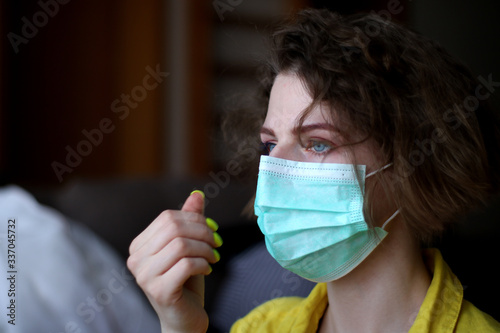 Young woman putting on medical mask. Caucasian woman with short hair and make-up protecting herself from viruses