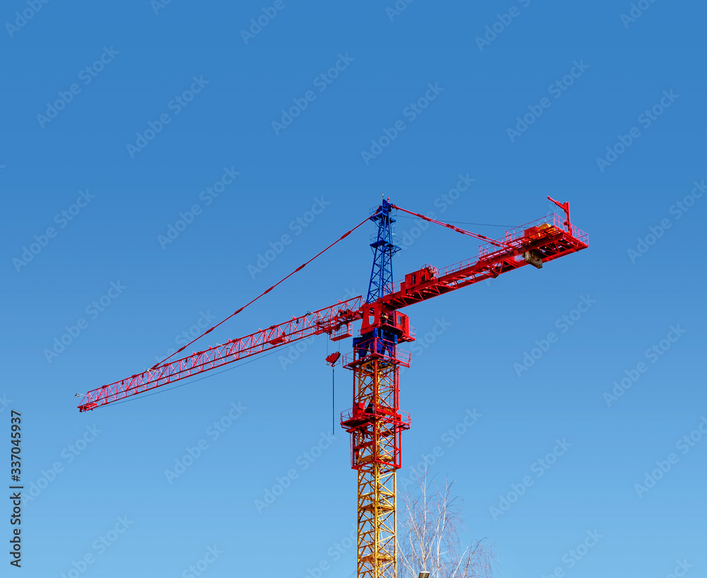 Tower crane red color on a blue sky background. Construction, industry, city development