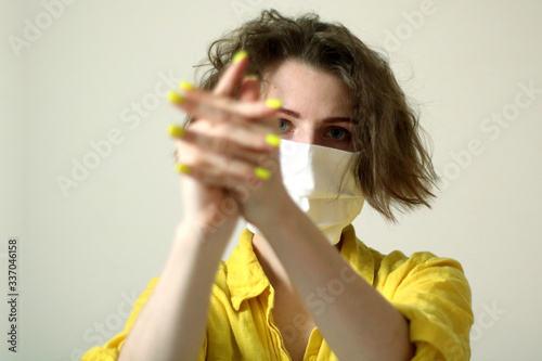 Young caucasian woman in medical mask washing hands with sanitizer. Girls wearing yellow shirt and manicure