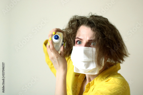 Young woman putting on medical mask. Caucasian woman with short hair and make-up protecting herself from viruses. Panic about pandemia and sanitizer