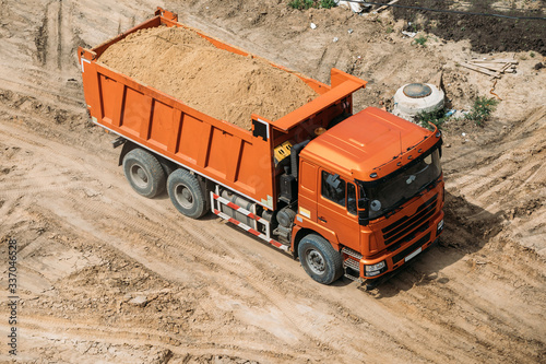orange dump truck rides on the sand top view