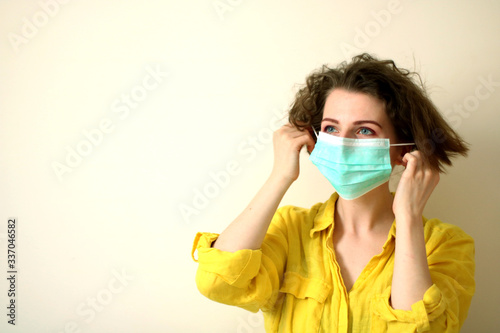 Young woman putting on medical mask. Caucasian woman with short hair and make-up protecting herself from viruses
