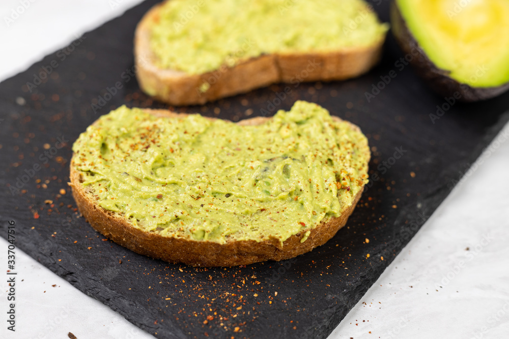 Avocado spread with grated chilly peppers on the sliced toasted bread Avocado spread with grated chilly peppers on the sliced toasted bread