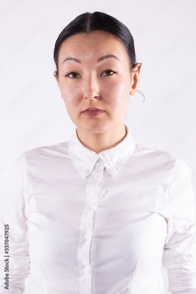 Asian woman with gathered hair looking seriously at camera. White background Asian woman with gathered hair looking seriously at camera. White background