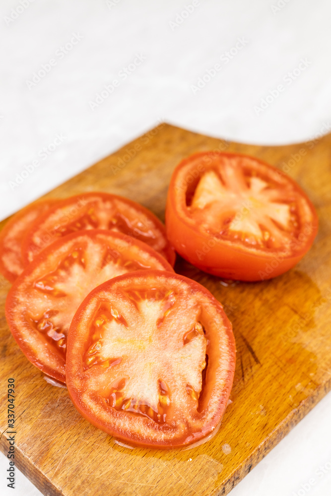 Sliced fresh tomato on the wooden cutting board with copy space Sliced fresh tomato on the wooden cutting board with copy space