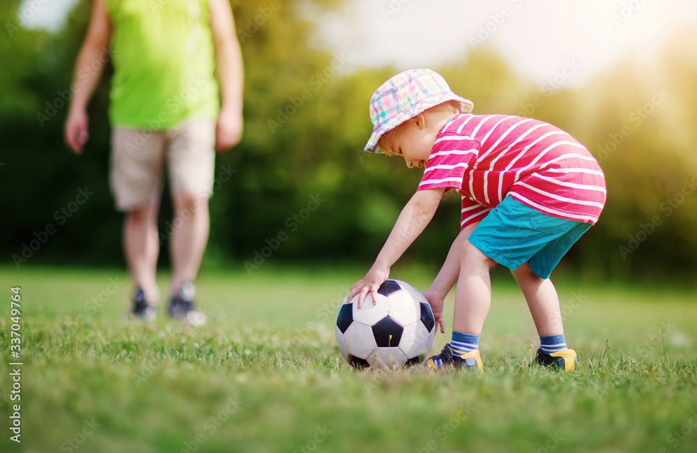 Little boy playting football on the field with gates Little boy playting football on the field with gates