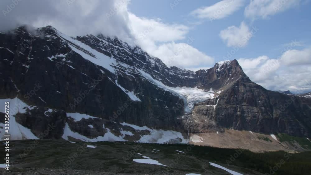 Panning shot of Angel Glacier melting into a lake below at Mt Edith Cavell in Japser during summer from the top of a trail Panning shot of Angel Glacier melting into a lake below at Mt Edith Cavell in Japser during summer from the top of a trail