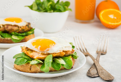 European breakfast, sandwich with fried egg, chicken, herbs and orange juice. Breakfast on a light table, top view. Food background.