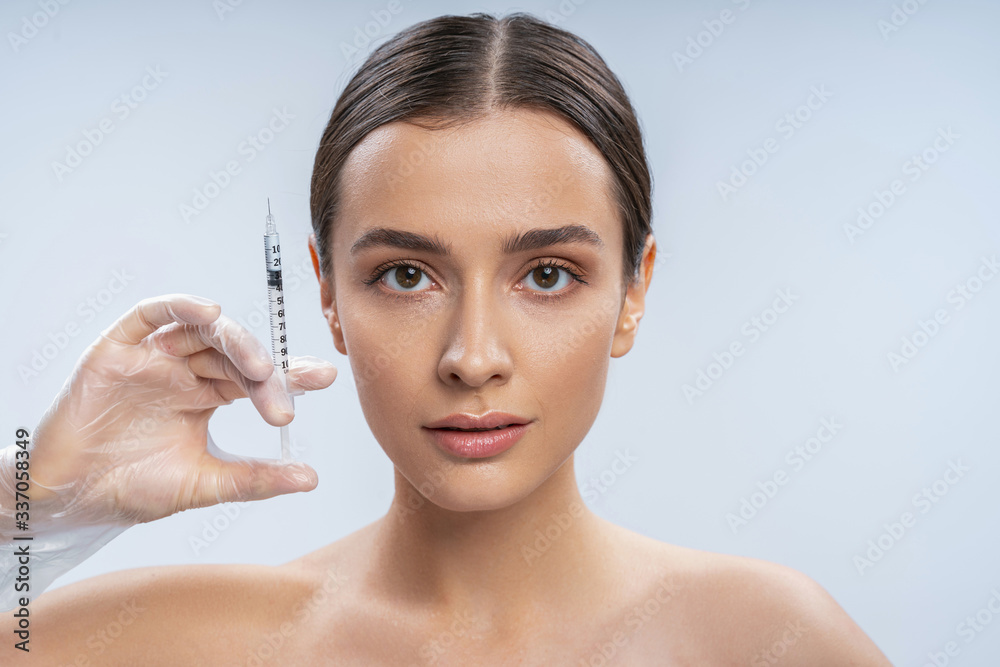 Young pretty female doing face botox injections