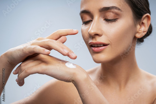 Young woman applying body care on hand