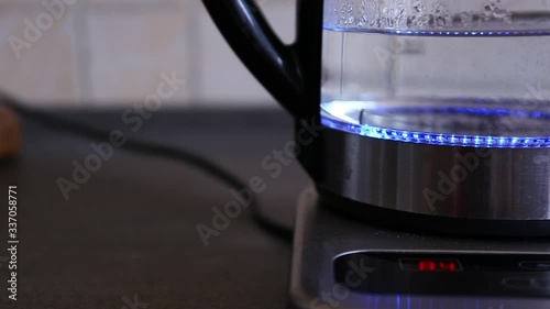 Boiling water in an illuminated modern kettle reaching 100 celsius degrees photo