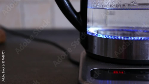 Boiling water in an illuminated modern kettle reaching 100 celsius degrees