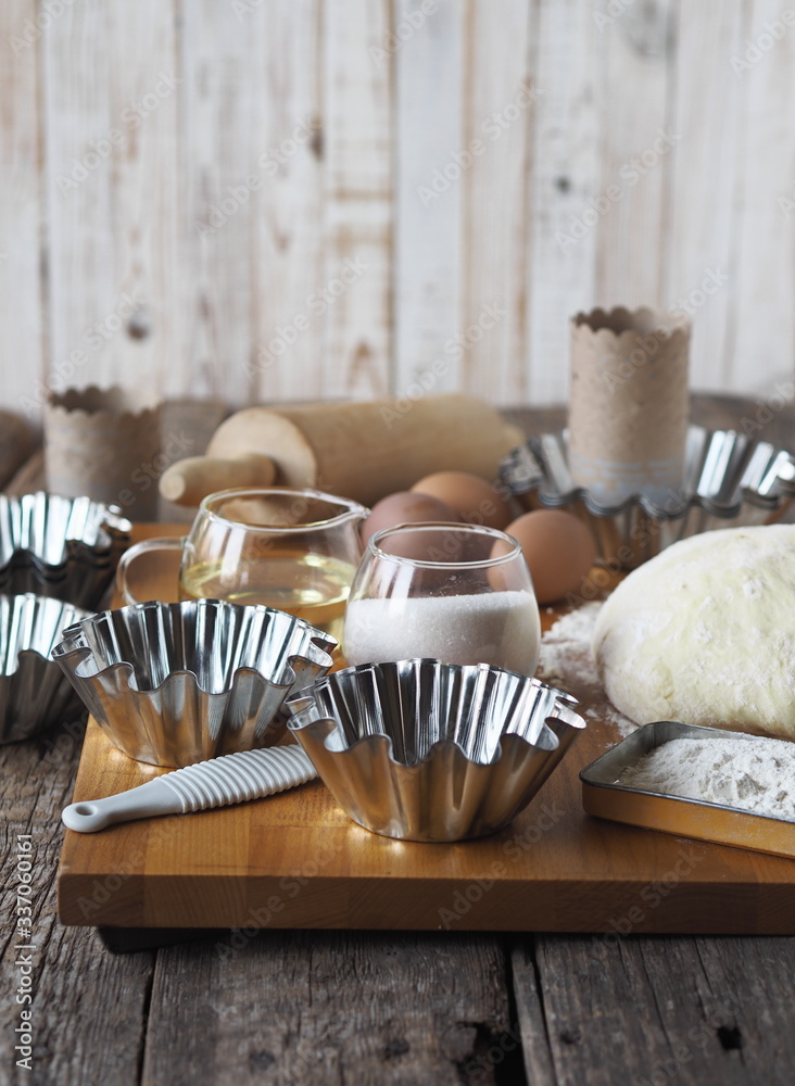 Dough for Easter cakes, croissants, or bread on the background of molds for Easter cakes and ingredients for kneading dough. Dough for Easter cakes, croissants, or bread on the background of molds for Easter cakes and ingredients for kneading dough.