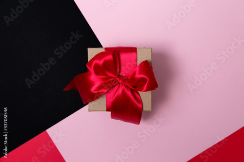 Craft box with a large red bow on a paper background. Flat lay.