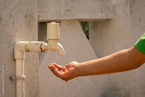 kid hand wait for water drop to drink from fiber pipe line tap on white background