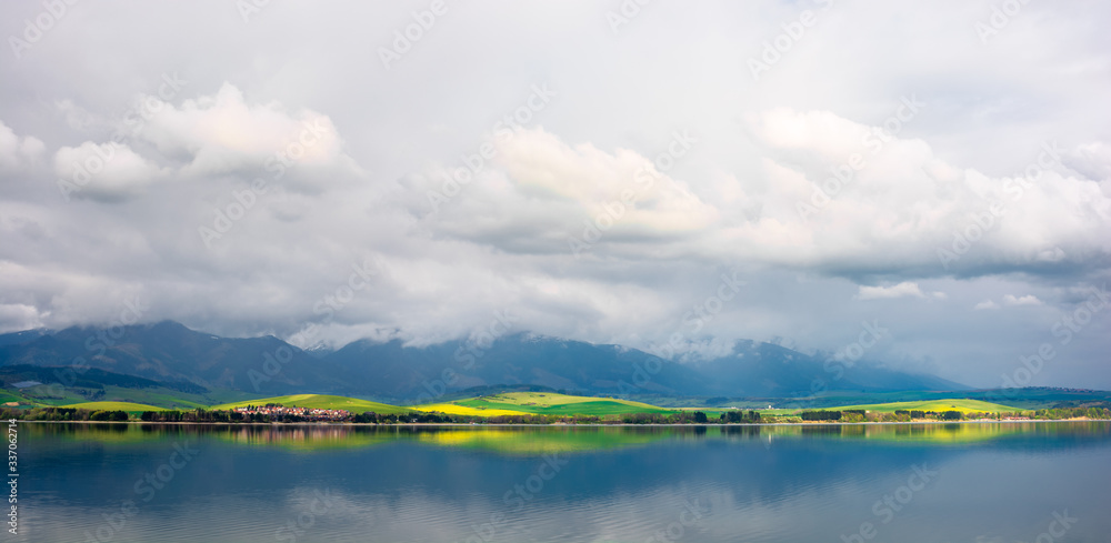 lake in mountains. cloudy day in springtime. beautiful scenery of high tatra mountains in dappled light. amazing countryside of liptovska mara, slovakia