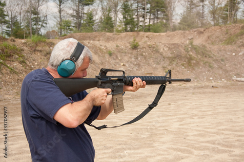man shooting AR-15 on a range, shell casing in air