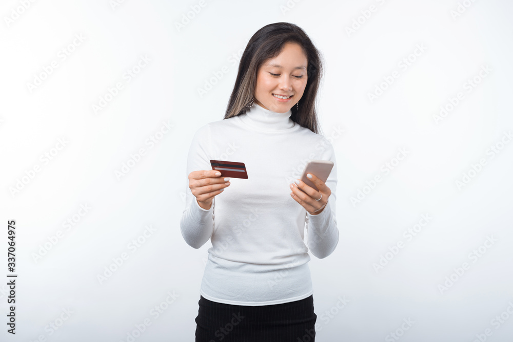 Portrait of happy young asian woman using credit card and smartphone over white background Portrait of happy young asian woman using credit card and smartphone over white background