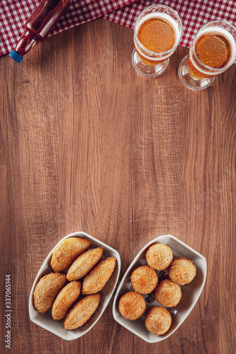 Brazilian appetizer deep fried cheese and beef croquette with two glasses of beer - Bolinha de queijo and risolis de carne in top view photo