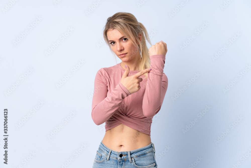 Blonde woman over isolated blue background making the gesture of being late Blonde woman over isolated blue background making the gesture of being late
