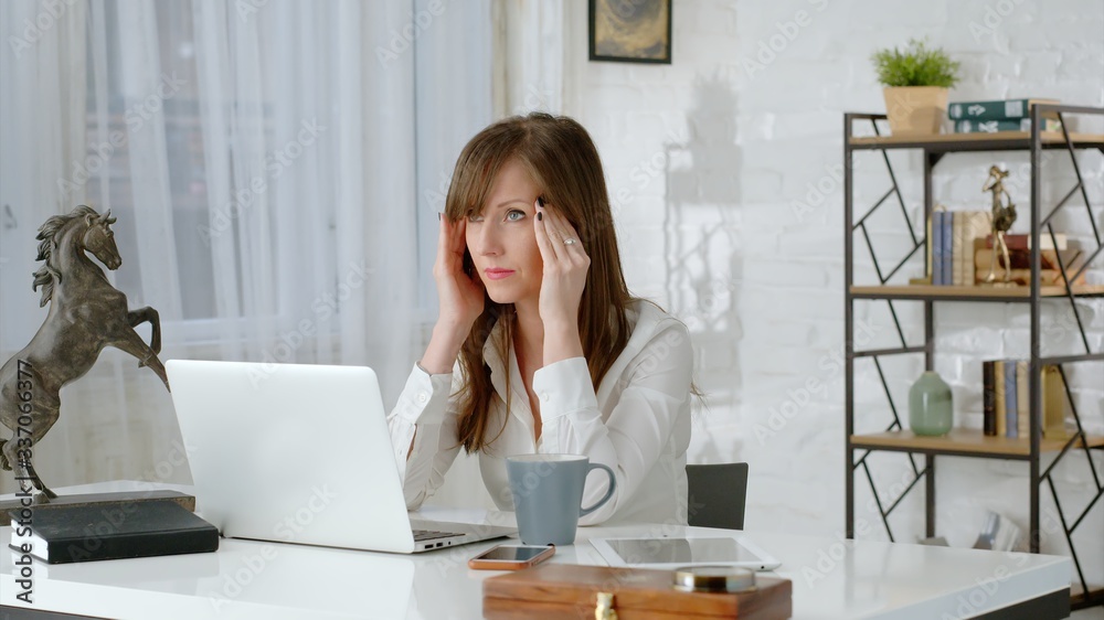 Young business woman working at desk with laptop computer in home office, thinking, having problem and headache . Zoom out. . Young business woman working at desk with laptop computer in home office, thinking, having problem and headache . Zoom out. .