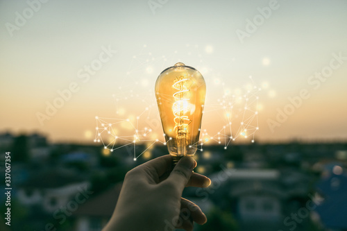 Foto Hand business man holding light bulb with light line
