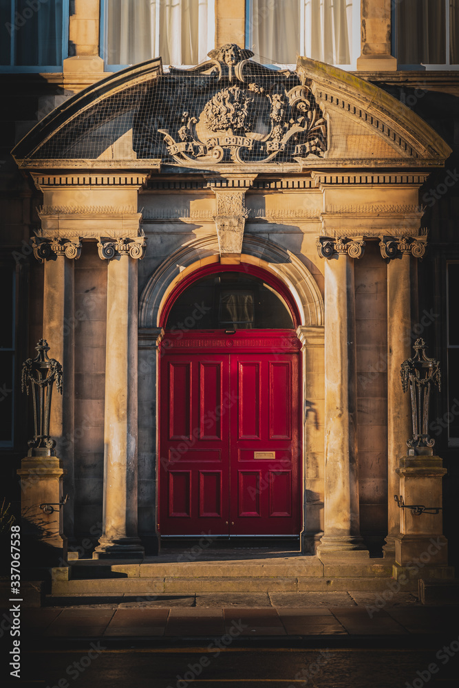 Classical architecture doorway inside sculptural arch with ionic columns by sides of antique ornate red door of house in Edinburgh, Scotland , UK
