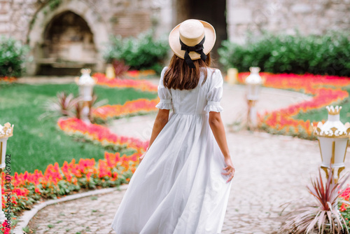 girl in a white dress and a straw hat walks in a beautiful park. bride in a vintage wedding dress in the garden.