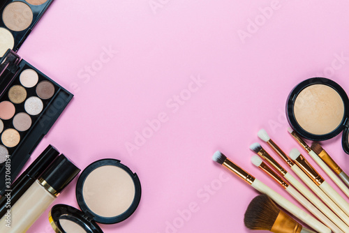 Makeup brushes, powder, eyeshadow palette, foundation for the face on a light pink background with place for text, top view