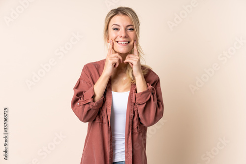 Blonde woman over isolated background smiling with a happy and pleasant expression