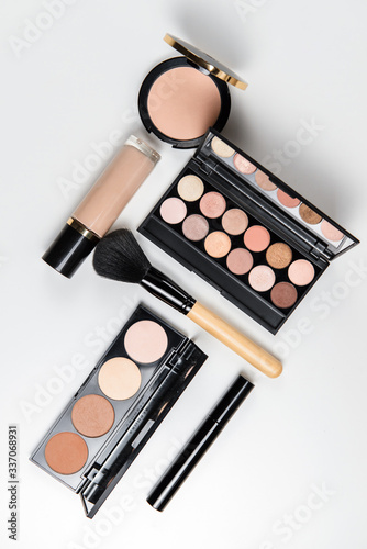 Makeup brushes, powder, eyeshadow palette, foundation for face tones on a white background with place for text, top view