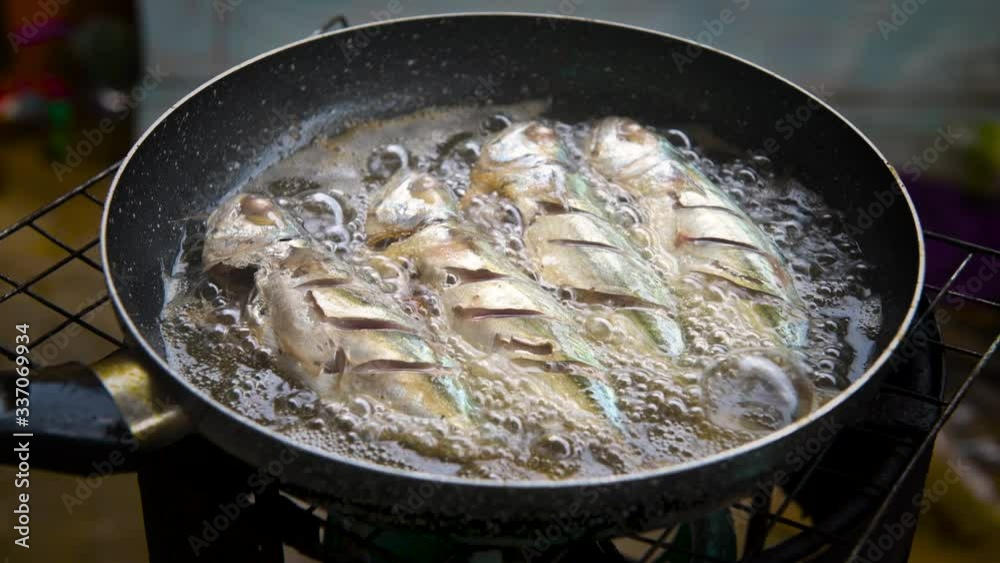 Frying mackerel fishes cooking with hot oil pan with 4K footage.