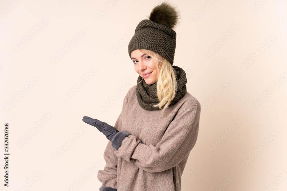 Young woman with winter hat over isolated background extending hands to the side for inviting to come Young woman with winter hat over isolated background extending hands to the side for inviting to come