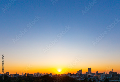 快晴の空に沈む夕日と街並み © makoto