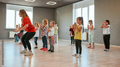 Group of little boys and girls dancing while having choreography class in the dance studio. Female dance teacher and children © Svitlana