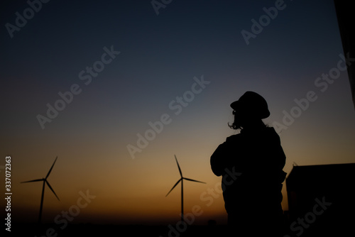 Silhouette of women engineer working and holding the report at wind turbine farm Power Generator Station on mountain,Thailand people