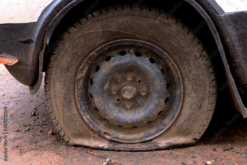 Punched wheel of a car on asphalt. Flat tire machine Punched wheel of a car on asphalt. Flat tire machine
