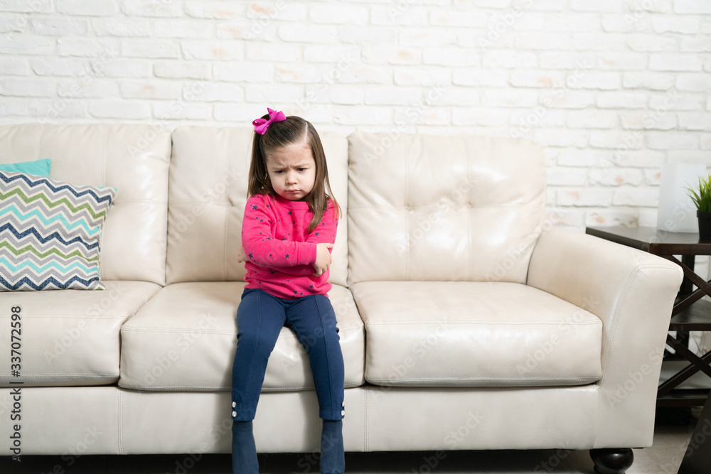 Serious little girl looking upset at home