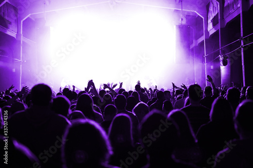 huge crowd in front of the stage at a music festival in purple light. banner or poster for the upcoming show. concert of a popular artist