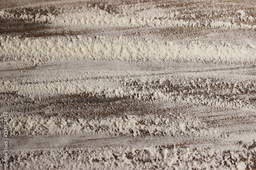 Blurry image of white flour on wooden background. Abstract food backdrop. White powder texture background.