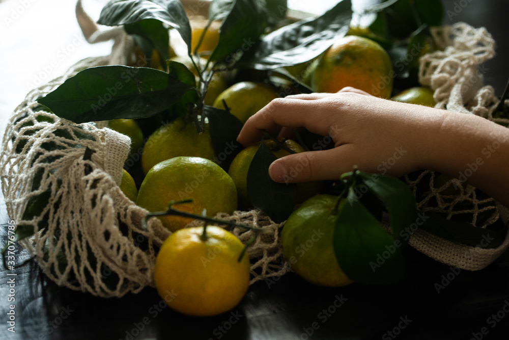 a child's hand picks up a tangerine from a bag