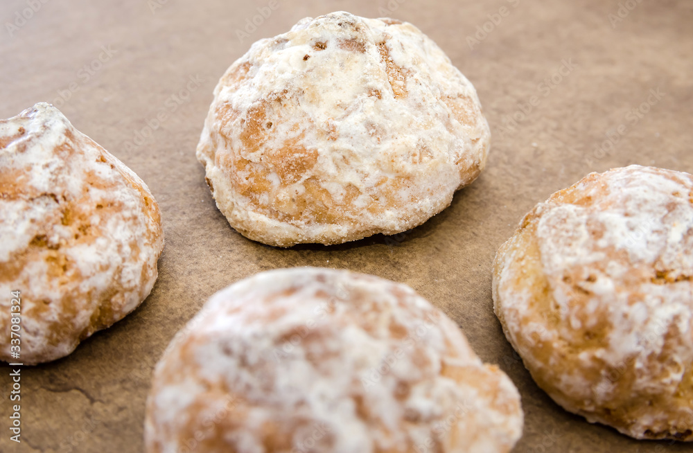 cookies in white icing with apricot jam inside on a wooden table. Close-up.