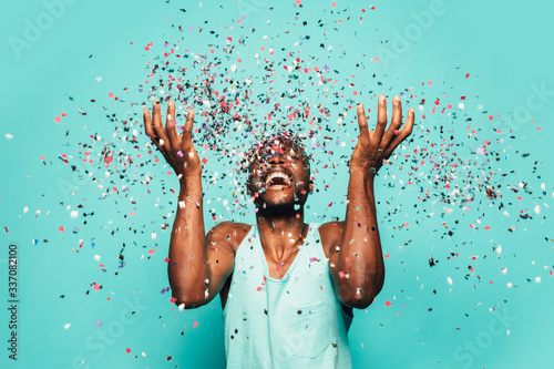 Cheerful black ethnic man throwing confetti on air. photo