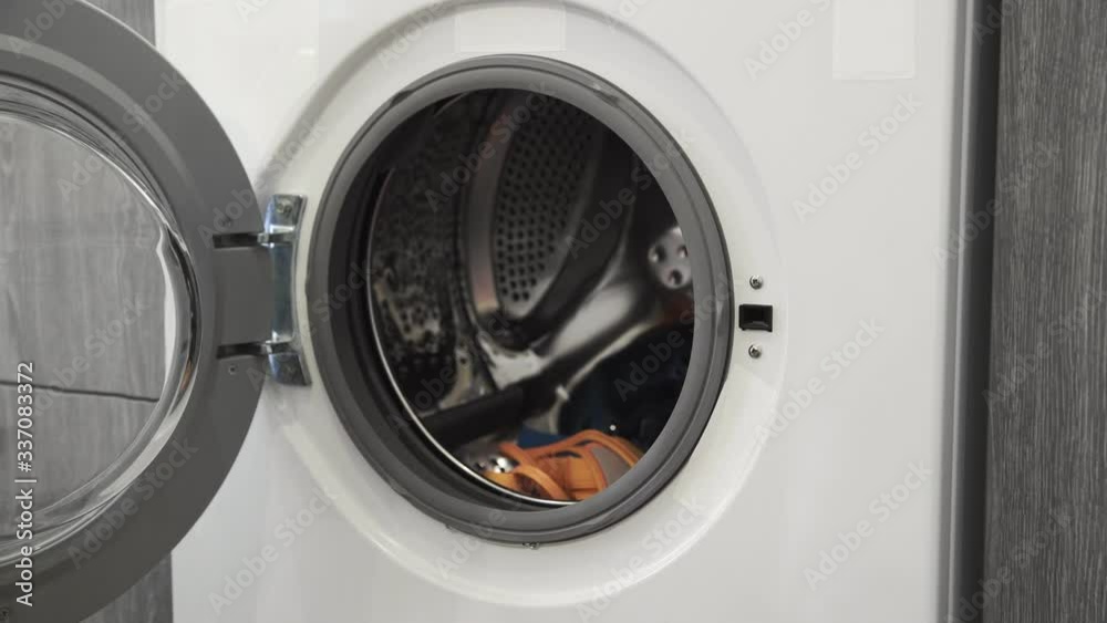 Female hand puts COLORED CLOTHES in laundry machine. Loading washing machine. Load clothes to washer machine. Load clothes laundry washing machine. Preparing laundry washing