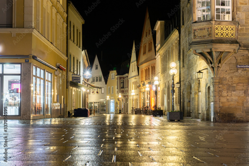 Leere Ladenstraße in einer Altstadt in Deutschland, Bayern. Leuchtende Schaufenster mit Laternen und beleuchteten Häuserfassaden. Keine Menschen oder Personen.