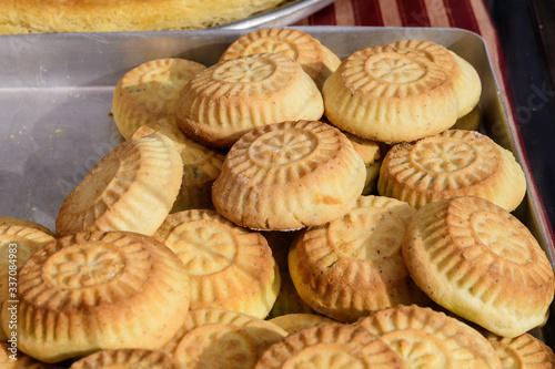 Close up of traditional oriental sweet filled pastry cookies known as mamul or Mamoul, Arab desert with sugar, walnuts and dates, in display at an weekend street food market, top view, soft focus 