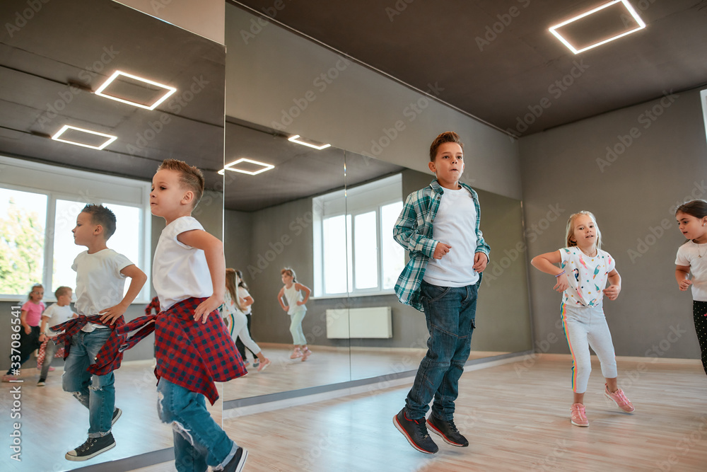 Fototapeta premium Full of energy. Little happy boys and girls running and jumping in the dance studio. Warming up before dance class