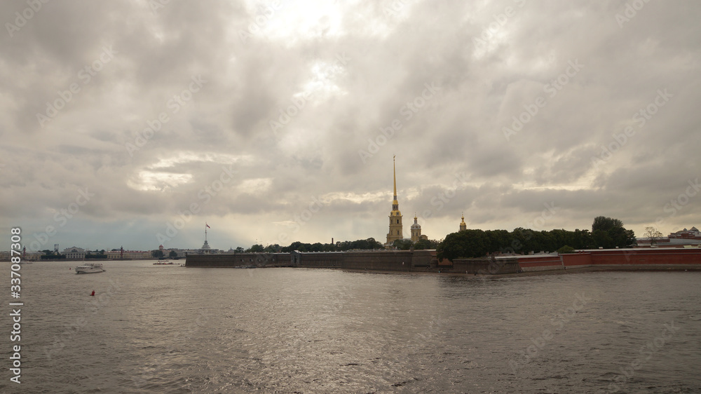 Peter and Paul Fortress is one of the attractions in the city of St. Petersburg in Russia. The evening sky is reflected in the Neva River, pleasure excursion boats sail by.