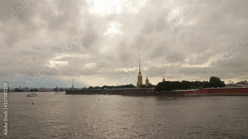 Peter and Paul Fortress is one of the attractions in the city of St. Petersburg in Russia. The evening sky is reflected in the Neva River, pleasure excursion boats sail by.
