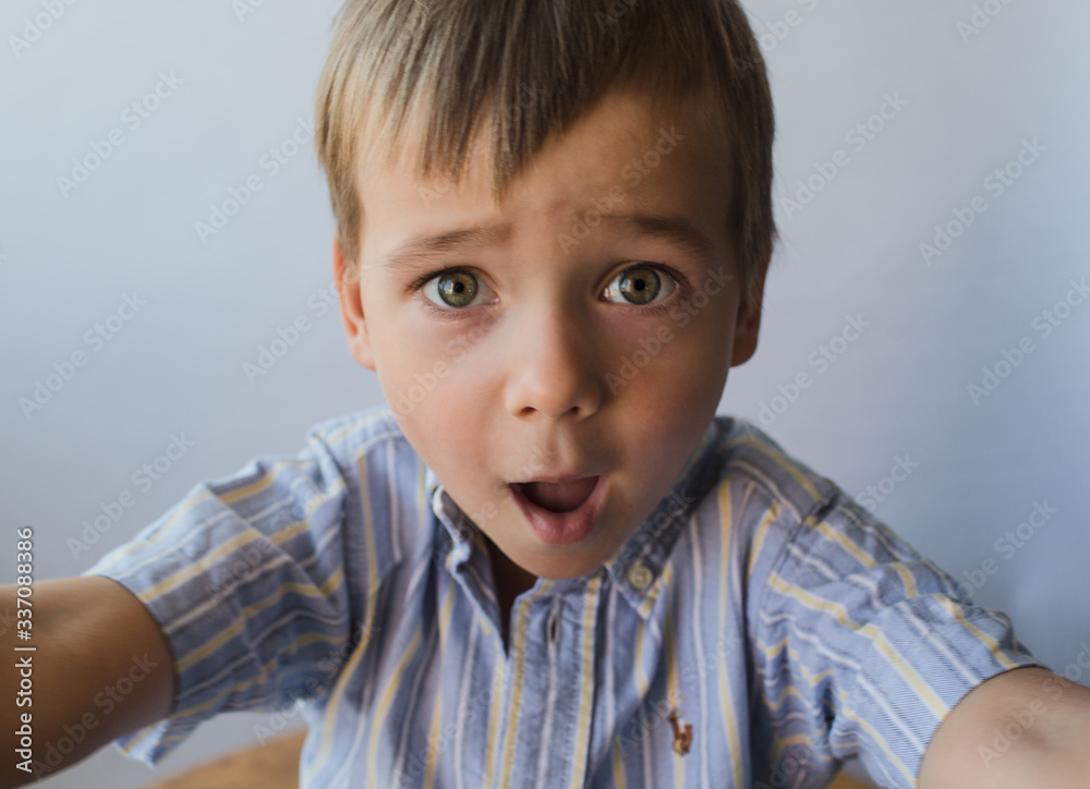 A child in a blue shirt on a white background looks at the frame in surprise. A child in a blue shirt on a white background looks at the frame in surprise.